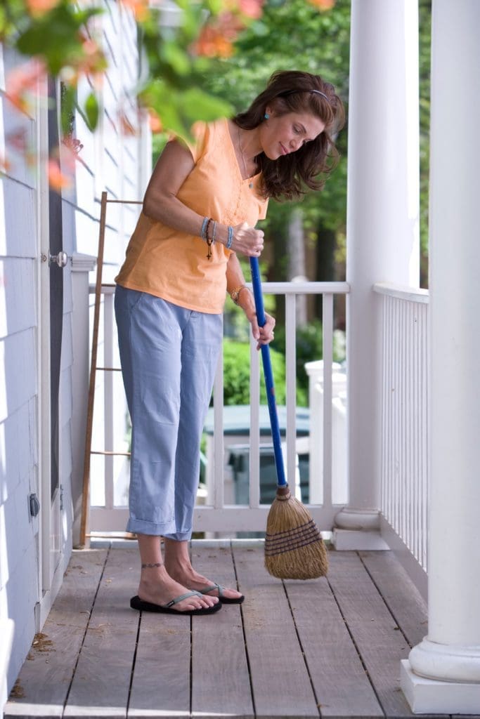 Femme qui passe le balais sur une terrasse