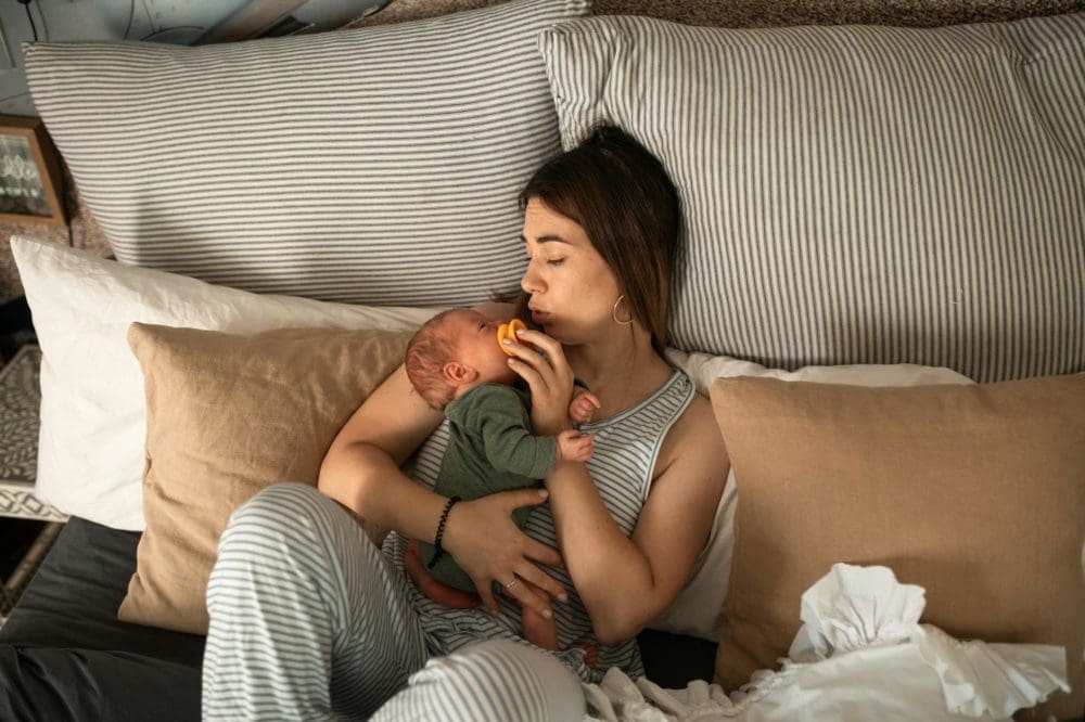 a woman lying down while carrying her baby