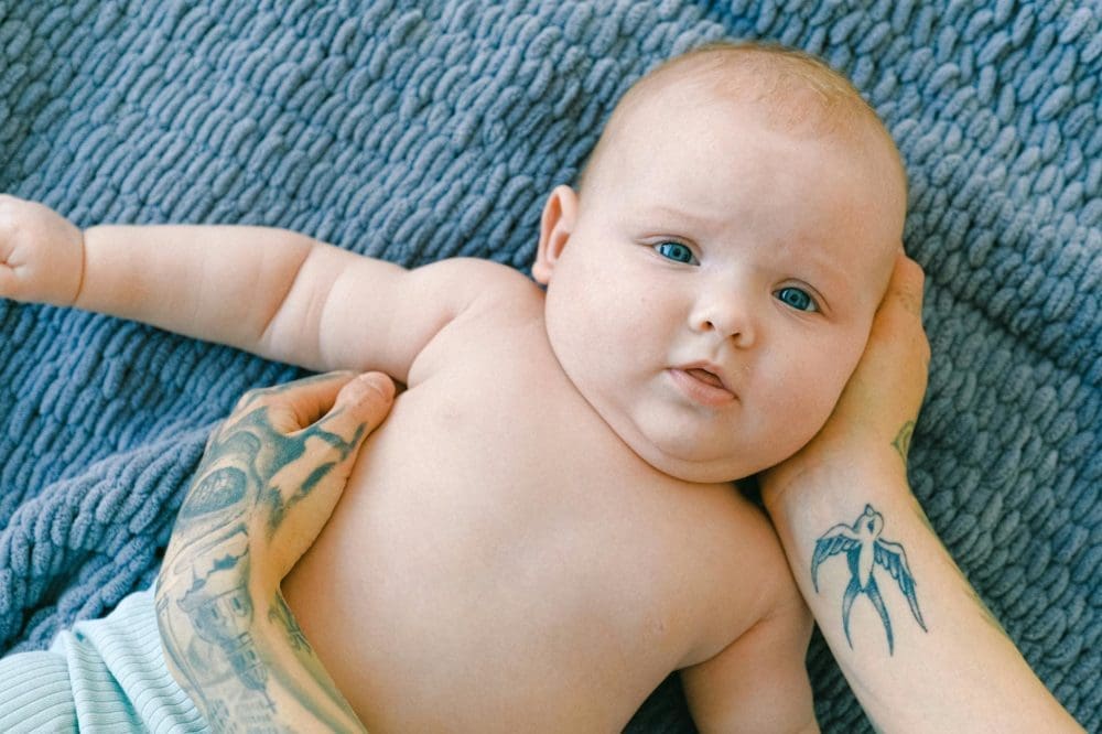 topless baby lying on bed